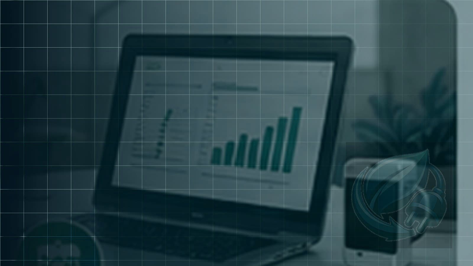 A laptop showing an asset report on screen beside a phone on a desk